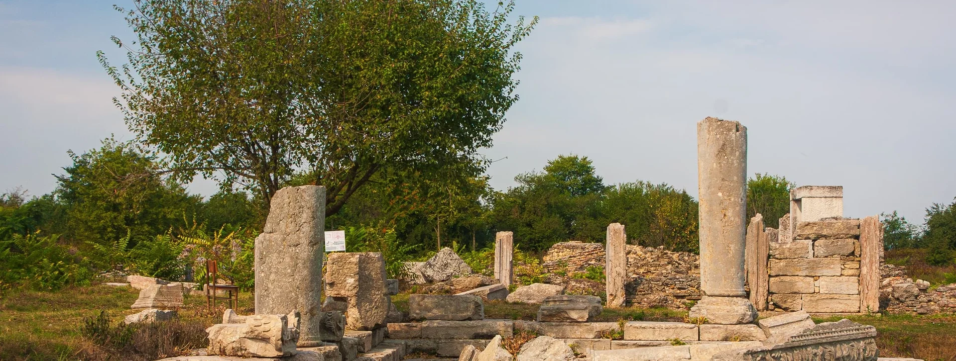 Ruins of Nicopolis and Istrum surrounded by green trees under bright daylight.