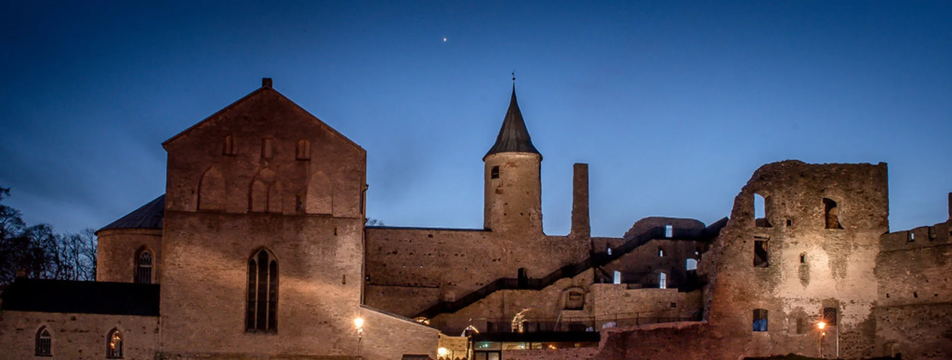 Haapsalu Castle and its museum illuminated by streetlights at night under a clear sky.