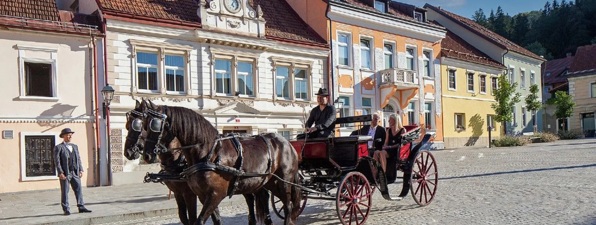 Horse-drawn carriage passing historic buildings in Šoštanj, Slovenia.