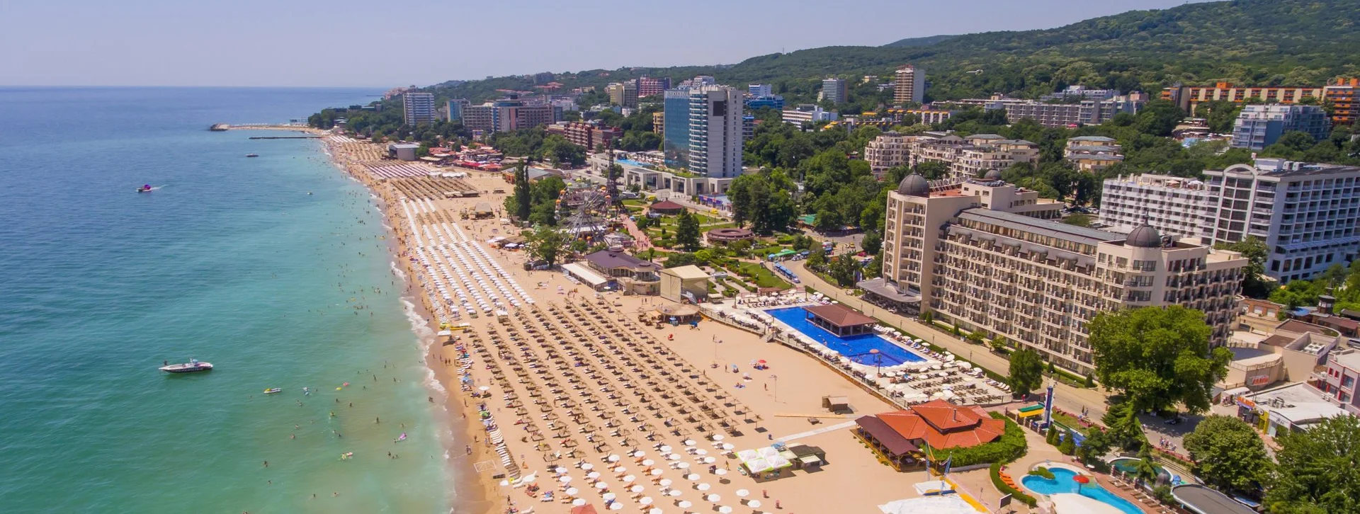 Plage de Golden Sands sur la côte de la mer Noire, Bulgarie — vaste étendue de sable doré avec une eau bleue limpide et des collines boisées à l’arrière-plan.
