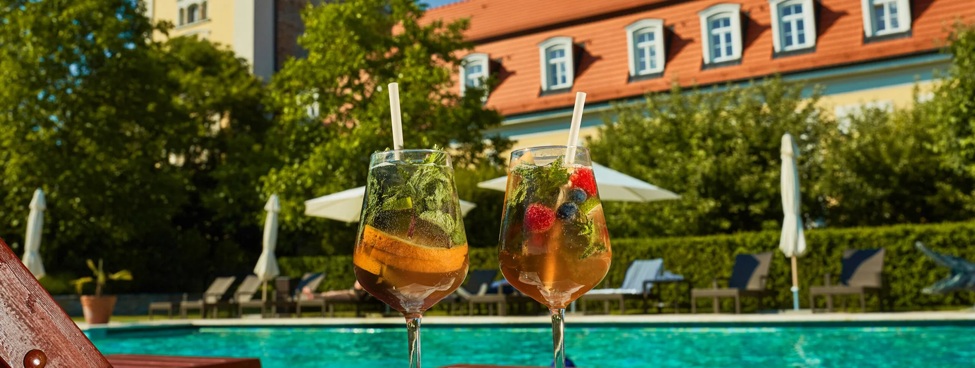 Two summer cocktails by a hotel pool.