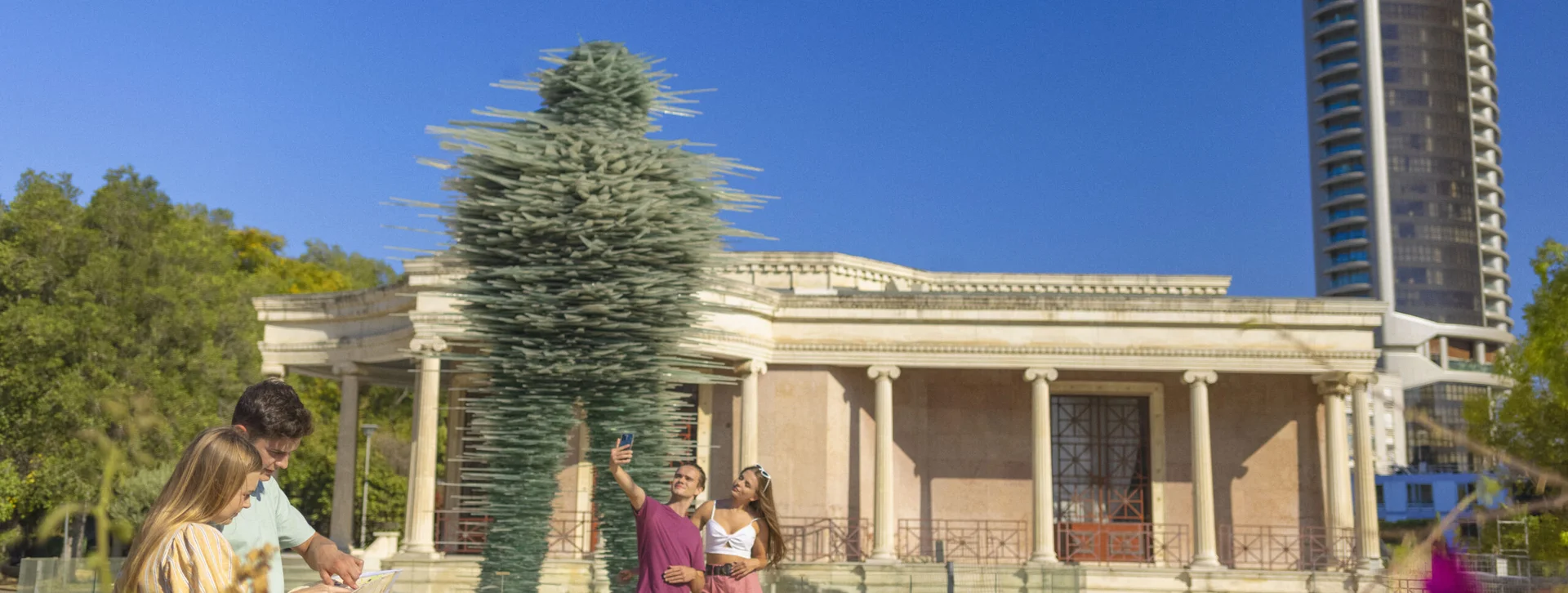 Visitors taking photos near a modern sculpture outside a neoclassical building in Nicosia