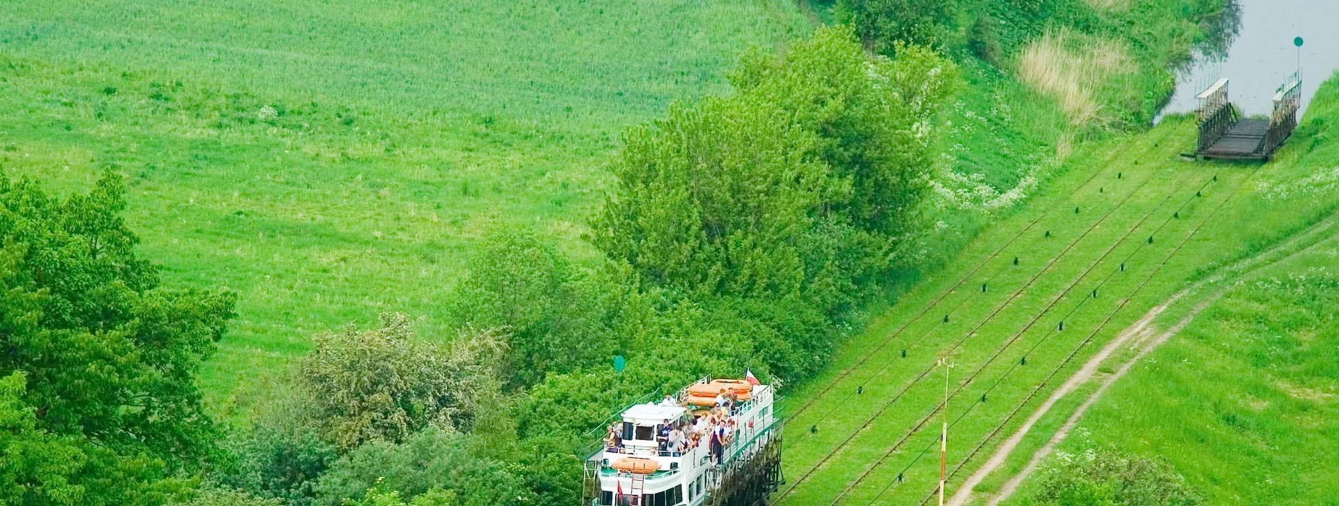 A boat on tracks surrounded by lush green landscape and trees.