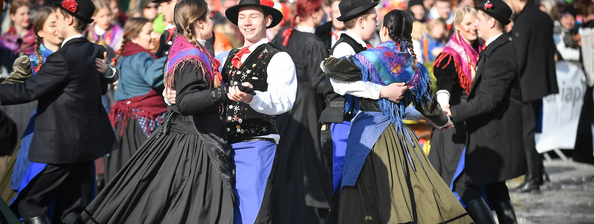 People dancing in traditional costumes at an outdoor festival.
