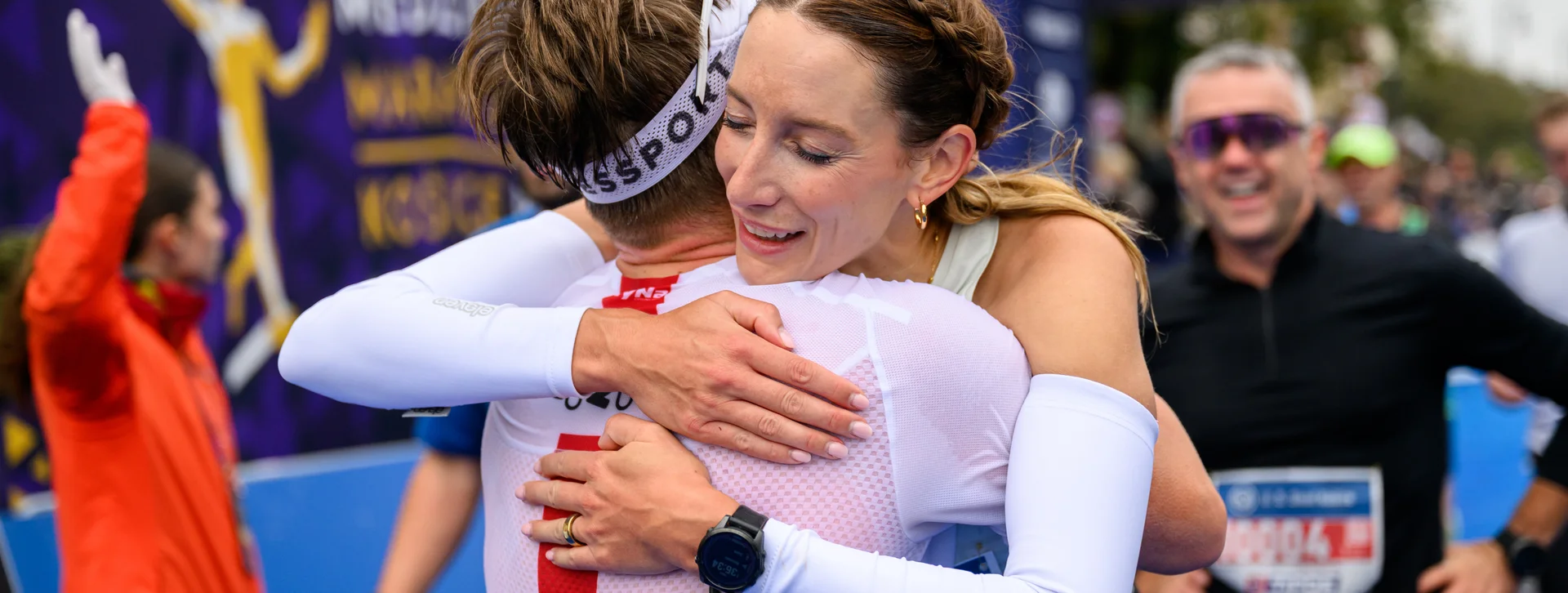 Two marathon runners joyfully hugging at the finish line, smiling with relief and happiness.