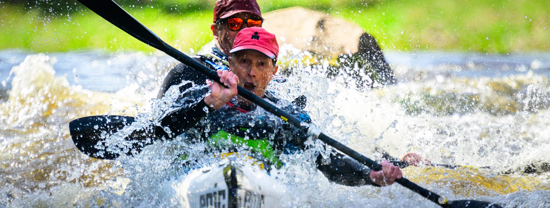Two people kayaking through whitewater rapids, concentrating intensely.
