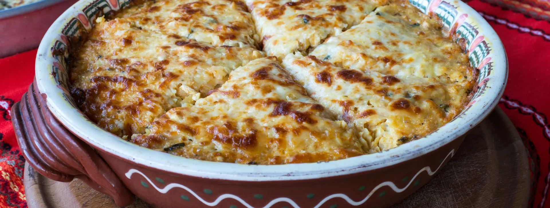 Baked casserole with a golden cheese crust, one slice slightly removed.