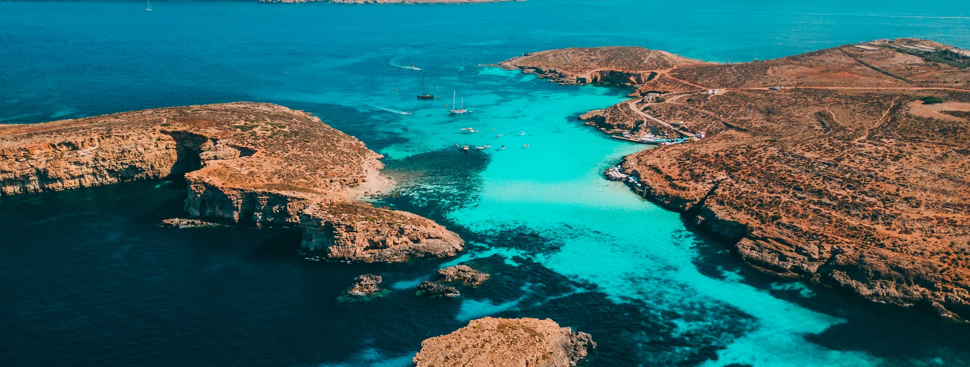 Clear turquoise water surrounded by rocky islands under a blue sky.