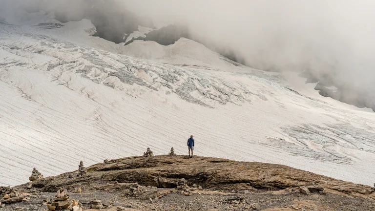 The top of a brown mountain with snow all around.