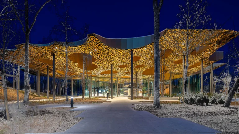 House of Music, a modern building with a unique, wavy golden roof at twilight, surrounded by bare trees.