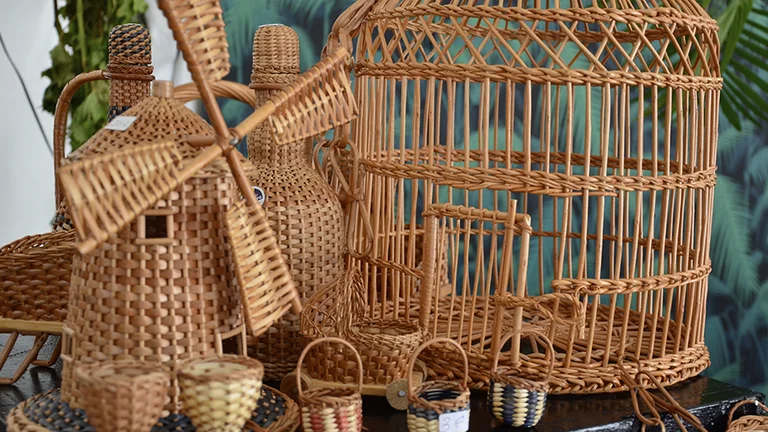 A collection of woven wicker items, including a windmill, birdcage, and various small baskets, displayed on a table.