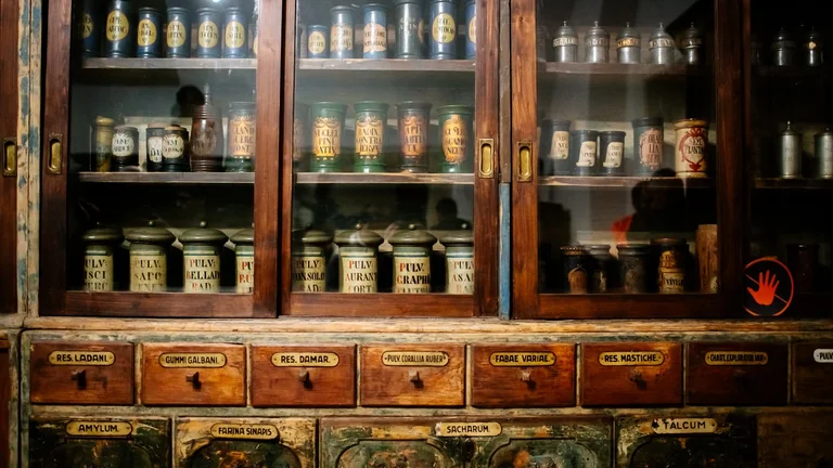 A vintage apothecary with dark wood cabinetry, jars of herbs, and a classic checkered floor, exuding an old-world charm.