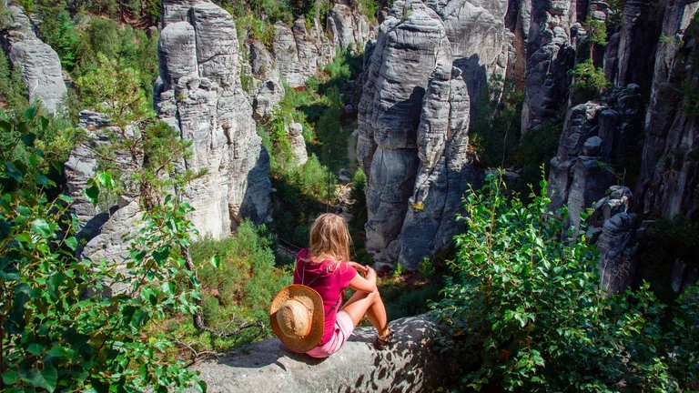 Woman admiring the dramatic sandstone formations of Prachov Rocks in Czech Paradise, a popular hiking destination in the Bohemian Paradise Geopark.