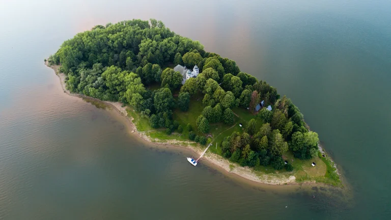 Aerial view of Slanica Island covered with dense trees on a lake.