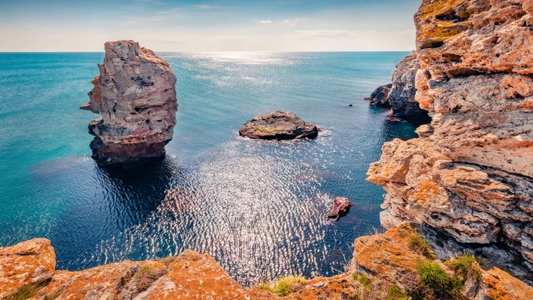 Dramatic sea cliffs with tall rock formations in the water.