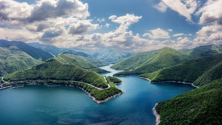 Winding reservoir surrounded by forested mountains.