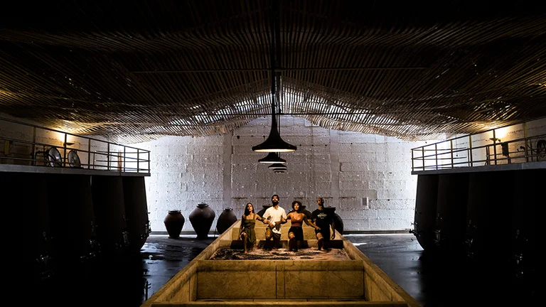 Visitors exploring a traditional Portuguese wine cellar with amphorae and fermentation tanks at Herdade do Esporão.