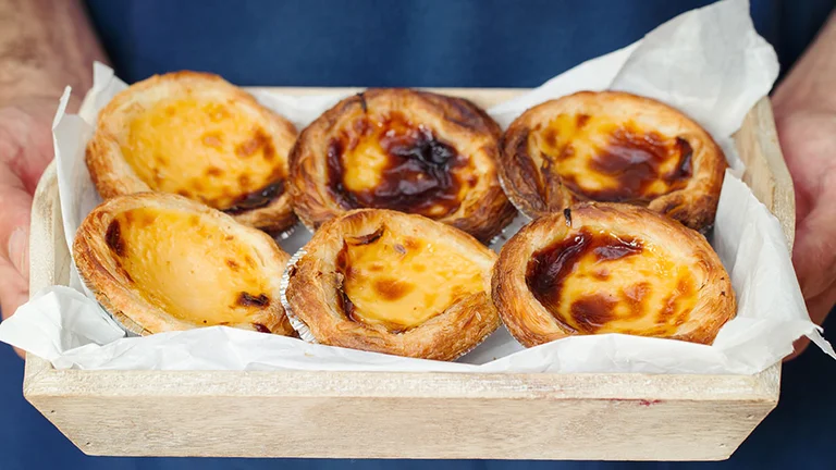 Famous Portuguese custard tarts, Pastéis de Nata, with flaky pastry and caramelized tops.