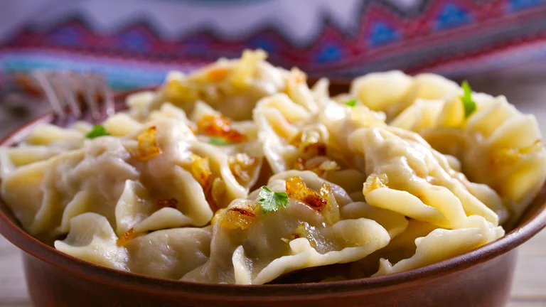 Polish traditional dumplings served in a bowl topped with fried onions.