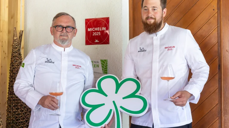 Chefs at Hotel Plesnik, a Michelin-recognized restaurant in Slovenia, holding wine glasses and a clover symbol.