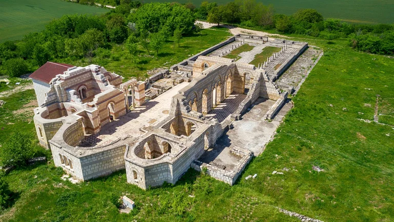 Aerial view of the Pliska ruins of the Great Basilica, showing stone walls and foundations surrounded by grassy fields.