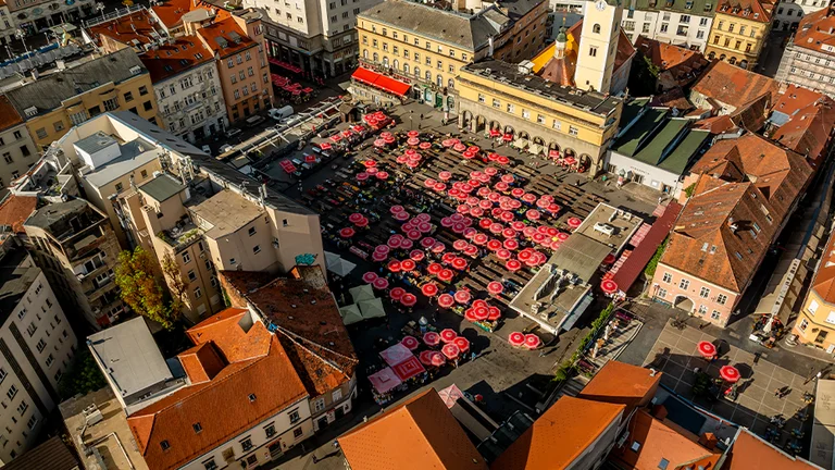 This image is an aerial view of Dolac Market, a well-known open-air farmers market in Zagreb, the capital of Croatia. It's located just above the main city square (Ban Jelačić Square) and is a vibrant hub for fresh produce, flowers, local goods, and traditional Croatian culture.