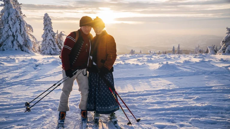 Couple ski touring at sunset in snowy mountain landscape.