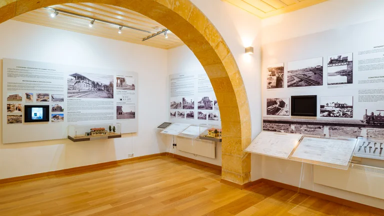 Modern museum room with wooden floor, informational displays, and photos on white walls.