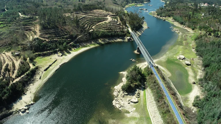 Aerial view of a river with a bridge crossing over lush, green landscape.