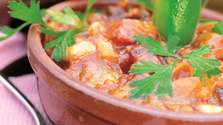Bowl of chili topped with parsley and a whole green chili pepper