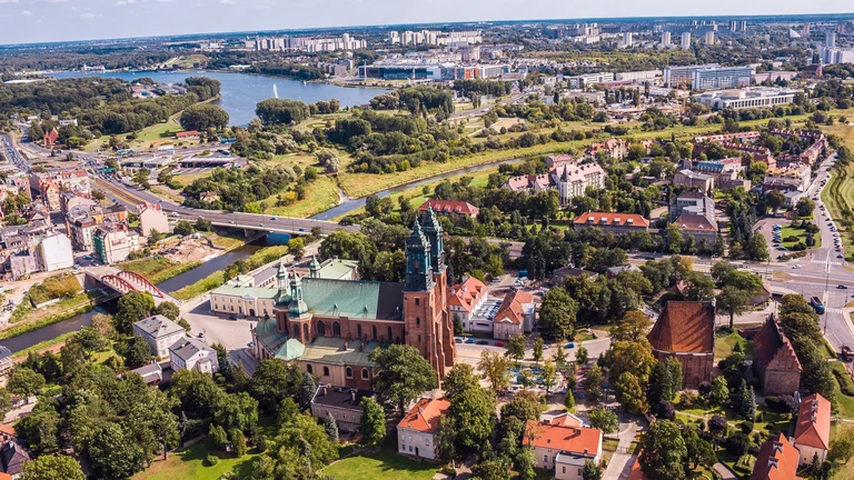 Aerial view of a city with a large church and river surrounded by greenery and buildings.