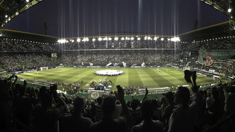 Crowded soccer stadium at night with bright lights and fans cheering.