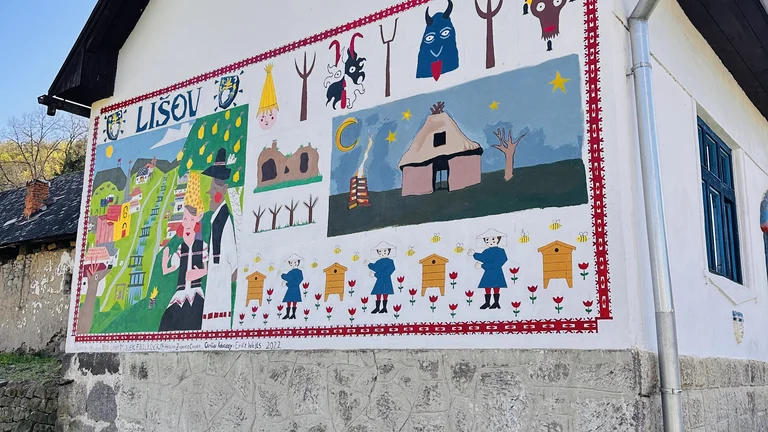 Colorful mural with animals, people, and buildings on the side of a white house.