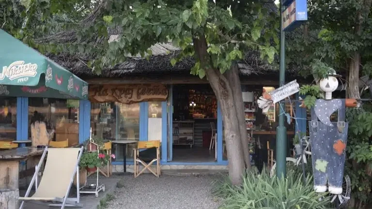 Cozy outdoor café with chairs, a tree, and a playful mannequin by the entrance.