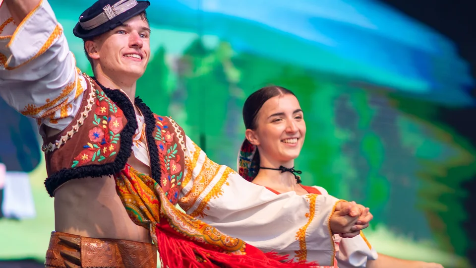 Two dancers in colorful traditional costumes performing on stage.