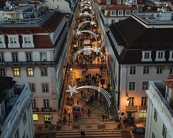 Aerial view of the Natal Baixa street in Lisbon with illuminated arches at twilight, between traditional buildings.