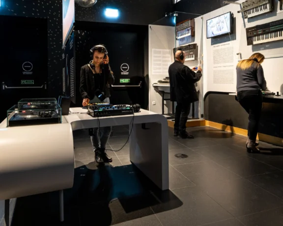 People interacting with music equipment in a modern exhibit.