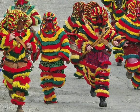 Colorful masked dancers in traditional costumes performing at the Caretos de Podence carnival.