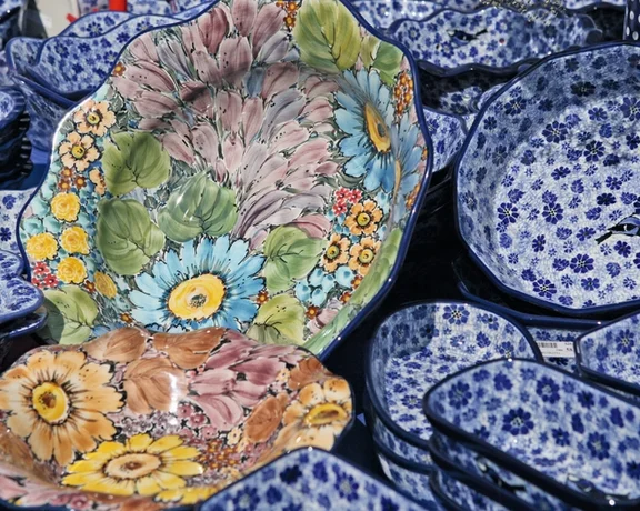 A vibrant display of ceramic dishes, featuring floral patterns and rich colors, arranged among various blue-patterned bowls and plates.
