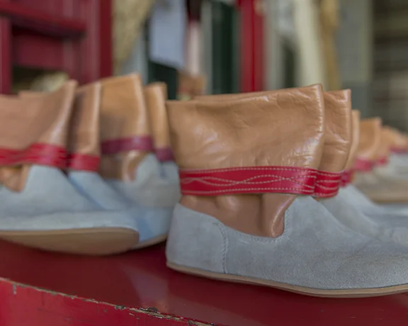 A row of boots featuring a soft brown leather upper and gray suede lower, set against a red background.