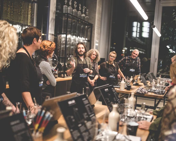A group of people engaged in a gin lab workshop, surrounded by tools and materials on a modern, wooden table.