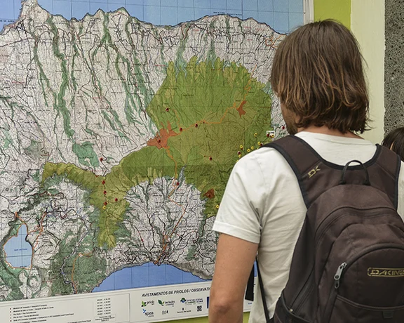 Two hikers looking at a detailed trail map in the Azores.
