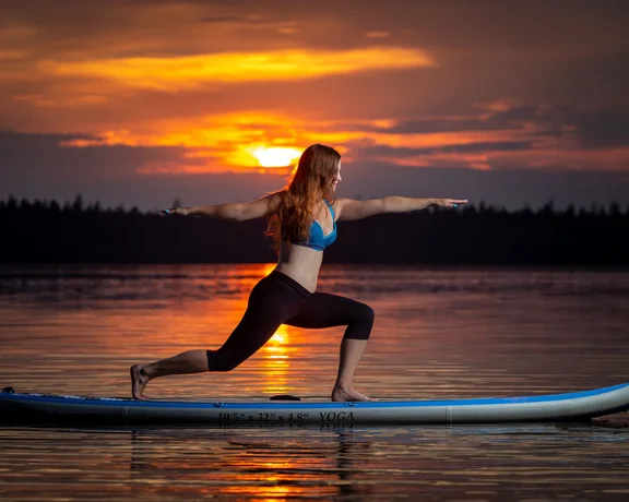 Woman practising yoga on a paddleboard at sunset on Lake Velké Dářko.