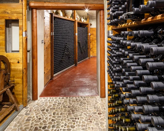 Traditional Cypriot wine cellar with rows of dark glass bottles stored on wooden racks.