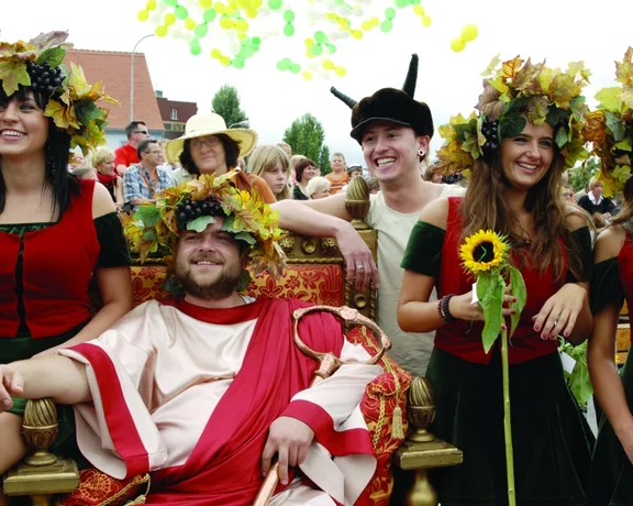 Group of people in traditional costumes with grapevine crowns celebrating the Winobranie wine festival in Zielona Góra, Poland.