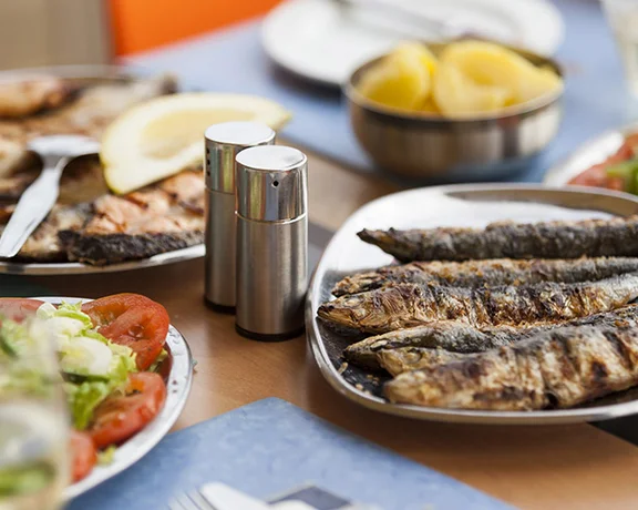 Traditional grilled sardines served with fresh salad, potatoes and white wine in Portugal.