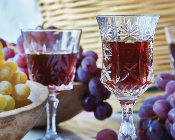Two glasses of amber-colored Commandaria wine set among ripe grapes, highlighting Cyprus’s rich wine heritage.