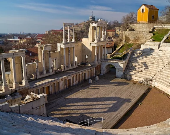 Angled view of the Ancient Theatre in Plovdiv, Bulgaria, showing its stone seating and stage framed by historic columns.