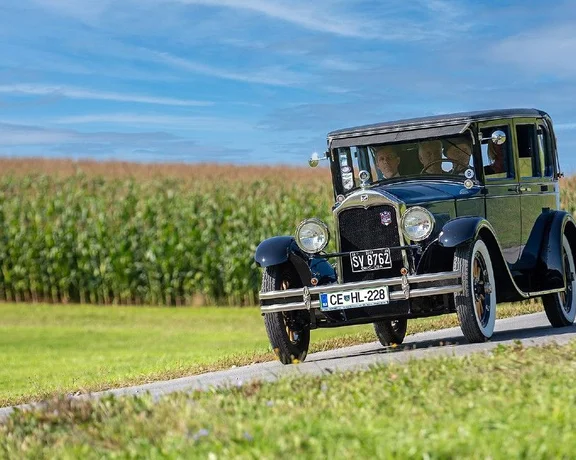 Vintage car driving through the Slovenian countryside as part of the Flight to the Tannery of Europe experience in Šoštanj.
