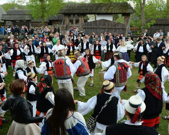 People in traditional Romanian clothing dancing in a large circle during a folk celebration in Maramureș.